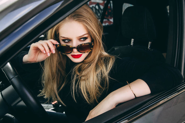 Stylish woman in sunglasses posing in black car - Foto, Imagem