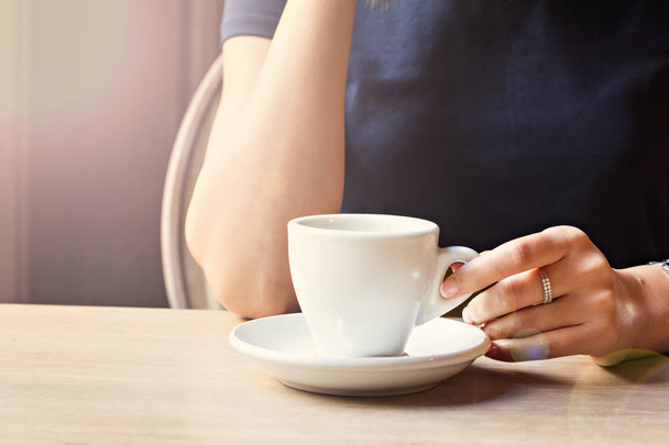Een kopje koffie in een café en een girl's handen. - Foto, afbeelding