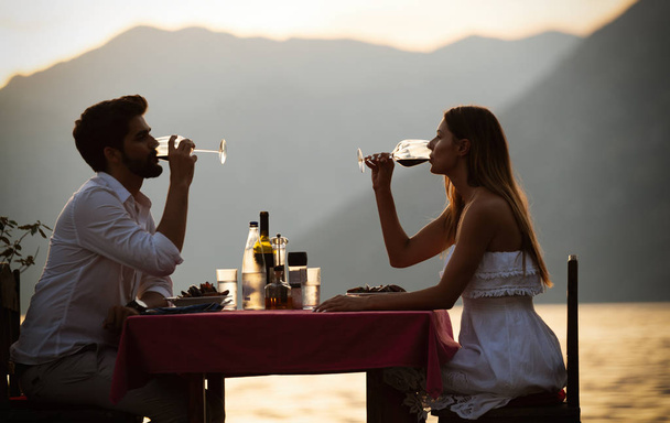 People, celebration, vacation, honeymoon and romance concept. Young couple enjoying a romantic evening dinner on the beach. - Foto, afbeelding