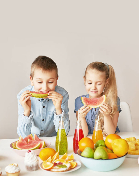 子供はフルーツパイナップル、スイカ、リンゴを食べ、チアと一緒に飲み物を飲みます。子供向けメニューのヘルシーフード - 写真・画像