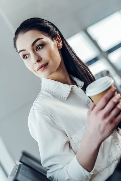 Carefree young woman is having hot drink in airport - Fotoğraf, Görsel