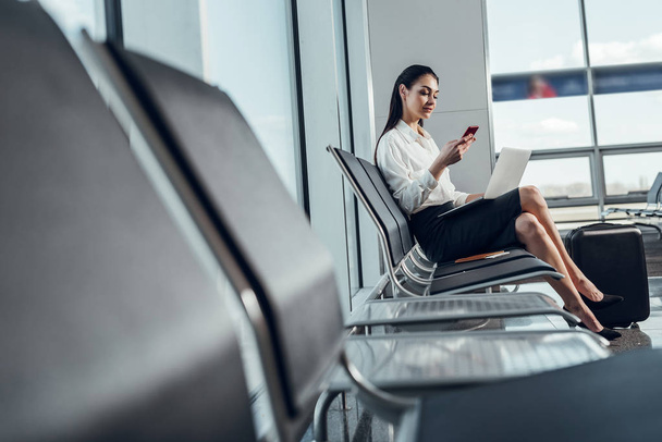 Cheerful woman is using gadgets before flight - Photo, image