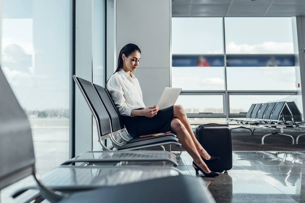 Calm businesswoman is waiting for departure with laptop - Fotó, kép