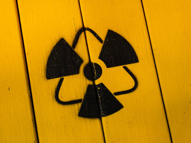 Teken van straling op een gele houten plank. - Foto, afbeelding