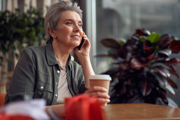 Relaxed smiling woman talking by phone in cafe - Φωτογραφία, εικόνα