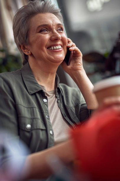 Happy smiling woman talking by phone in cafe - Fotoğraf, Görsel