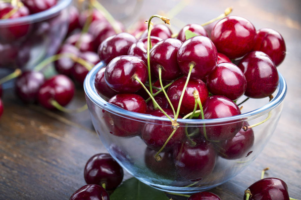 cherry in glass plate with wooden background.  - Foto, Bild