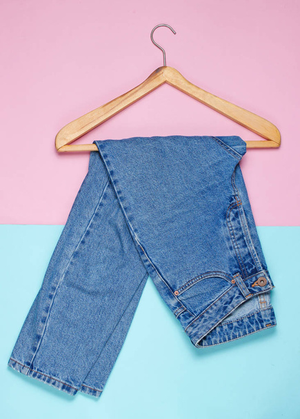 Top view, flat lay blue jeans with a wooden hanger on a pastel background. Minimalism - Foto, Imagem