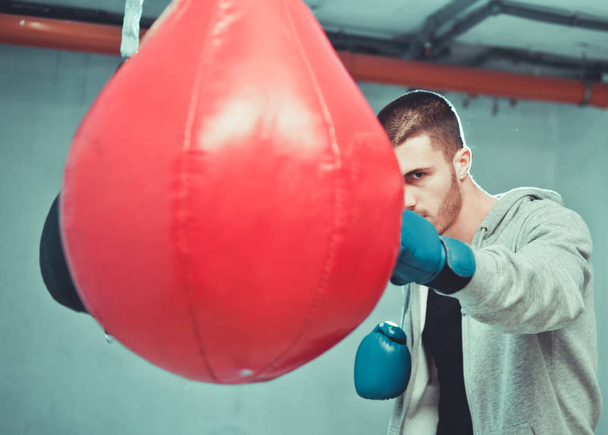Красивий концентрований чоловічий боксер тренує ручні удари з мішком для ударів
 - Фото, зображення