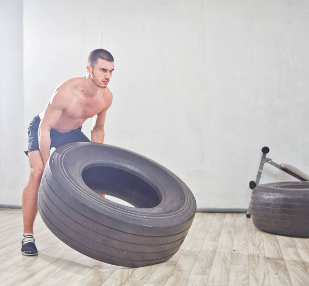 El joven deportista levanta una rueda de gran peso. proceso de formación. Entrenamiento funcional
 - Foto, imagen