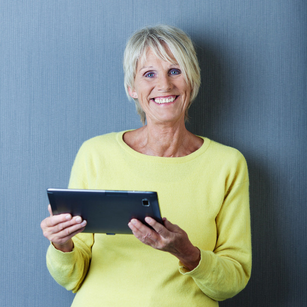 Senior woman working on a tablet and smiling - Foto, afbeelding