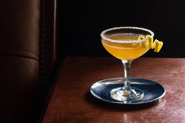 Chilled Sidecar Cocktail Served Up with Sugared Rim and Lemon Twist in Dark Luxurious Bar with Copy Space - 写真・画像