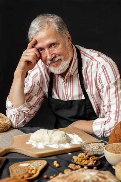 Elderly smiling professional chef man. Isolated over black background - Foto, immagini