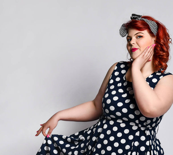 Pin up a female portrait. Beautiful retro fat woman in polka dot dress with red lips and manicure nails and old-style haircut - Foto, Imagem
