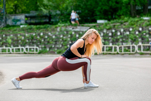 Fitness lifestyle. Young woman doing lunges to the side. Workout at the stadium. Healthy life concept. Horizontal photo - Foto, afbeelding