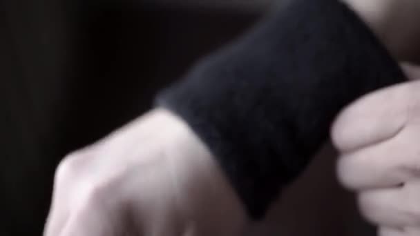 Sportoló visel fekete karpántok. Akció. Closeup a sportoló beállítja a csuklópánt a kezében, nem fáj a csukló alatt sport - Felvétel, videó