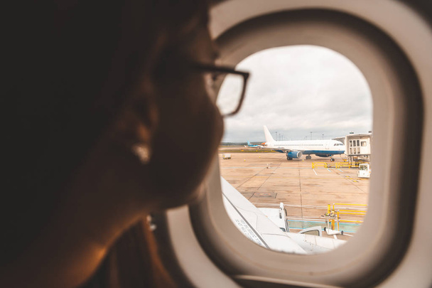 Mujer mirando por la ventana del avión en el aeropuerto
  - Foto, Imagen