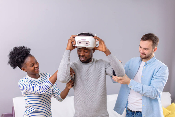 Multicultural friends help african guy to manade with vr headset for fist time - Fotoğraf, Görsel