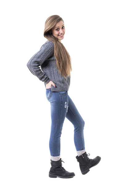 Красивая молодая милая девушка с руками в карманах позирует в сером вязаном свитере. Полное тело изолировано на белом фоне
.  - Фото, изображение