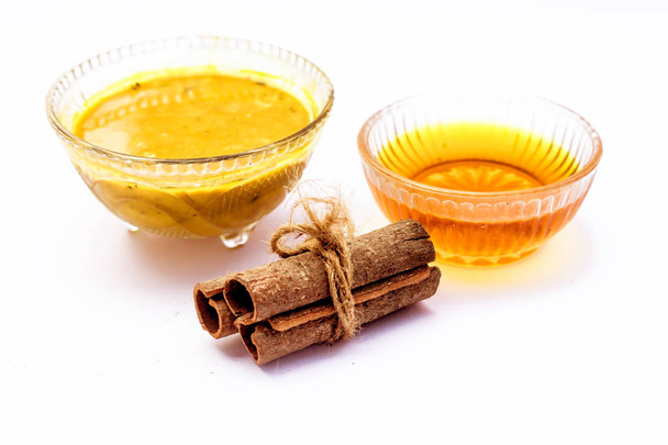 Cinnamon face pack isolated on white i.e. Cinnamon or tej powder well mixed with honey in a glass bowl and entire raw ingredients present on the surface,Used to clean acne and spots from skin. - Foto, imagen