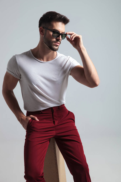Confident man looking to the side and adjusting his sunglasses - Photo, image