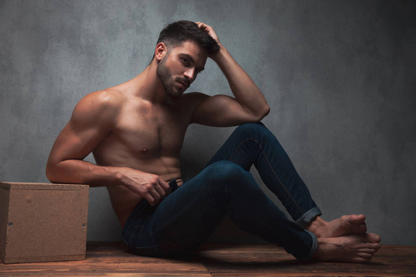 Confident topless young guy sitting and leaning on a box - Zdjęcie, obraz
