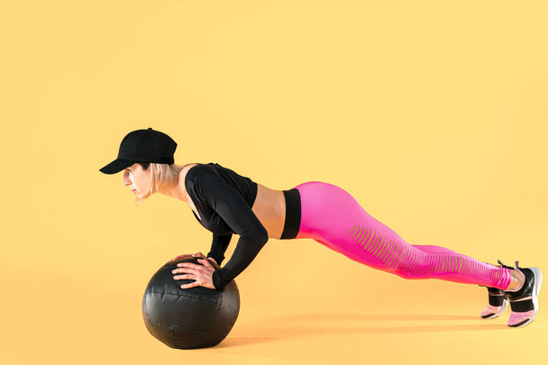 Woman in fitness clothes training with a medicine ball. Female athlete doing abdomen workout using a medicine ball - Photo, image