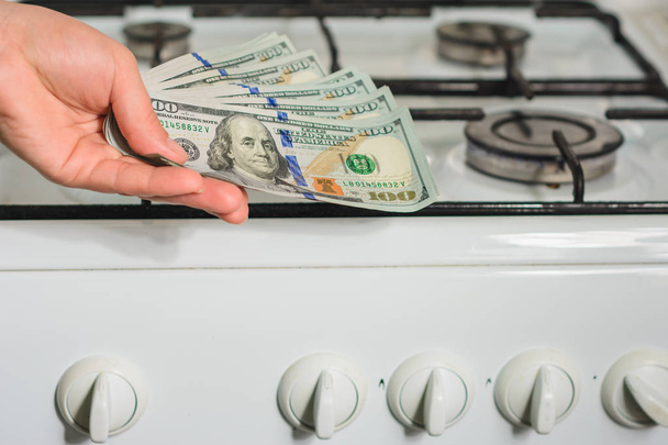 The man holds a bill of lading in his hands in a sign of the rise in price of natural gas near the gas stove. - 写真・画像