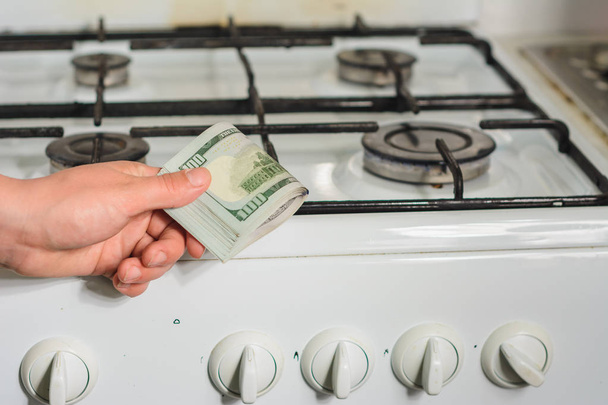 The man holds a bill of lading in his hands in a sign of the rise in price of natural gas near the gas stove. - 写真・画像