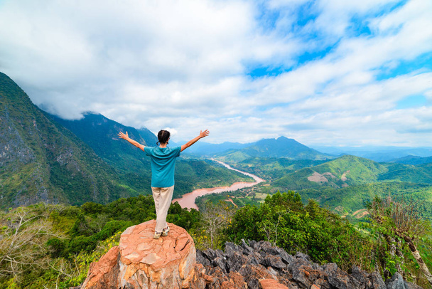 Woman with arms outstretched conquering mountain top at Nong Khiaw Nam Ou River valley Laos mature people traveling millenials concept travel destination in South East Asia - Fotó, kép
