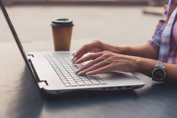 Młoda kobieta za pomocą laptopa podczas pracy na zewnątrz. Kobiece patrząc na ekran i pisania na klawiaturze. - Zdjęcie, obraz