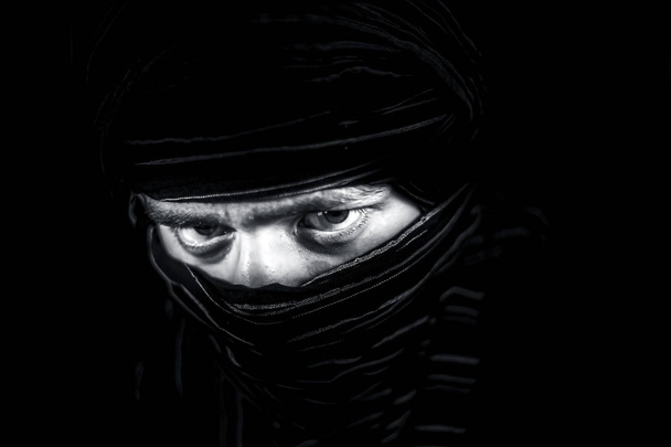 Uderzające portret męskiej nastolatek izolowane na czarno z przekłuwanie oczy wyraziste wraz z tkaniny obejmujące twarz z wyjątkiem oczu. Wyrażanie śmiałość i blonpota. - Zdjęcie, obraz