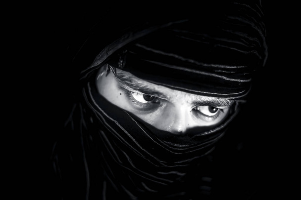 Uderzające portret męskiej nastolatek izolowane na czarno z przekłuwanie oczy wyraziste wraz z tkaniny obejmujące twarz z wyjątkiem oczu. Wyrażanie śmiałość i blonpota. - Zdjęcie, obraz