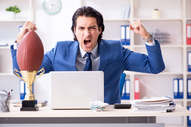 Giovane bell'uomo d'affari con palla da rugby in ufficio
 - Foto, immagini