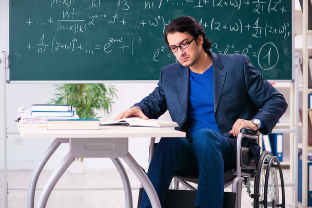 Młody przystojny mężczyzna w wózek inwalidzki przed chalkboard  - Zdjęcie, obraz