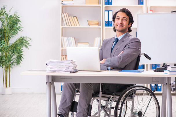 Mladý pohledný zaměstnanec invalidním vozíku v kanceláři  - Fotografie, Obrázek