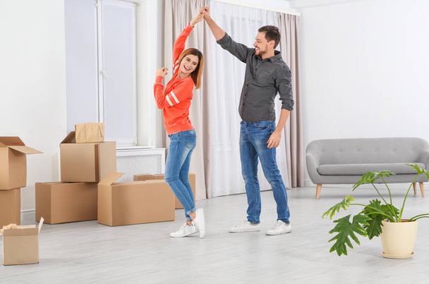 Happy couple dancing near moving boxes in their new house - Photo, Image
