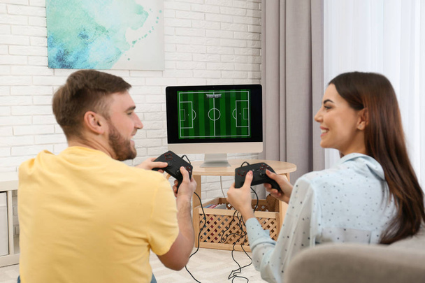 Happy young couple playing video games at home - Фото, изображение
