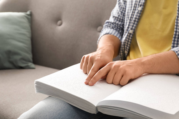 Blind man reading book written in Braille on sofa, closeup - Фото, зображення