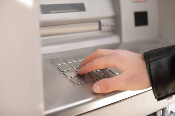 Man entering PIN code on cash machine keypad outdoors, closeup view - Photo, image