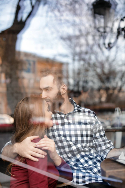 Lovely young couple spending time together in cafe, view from outdoors through window - Foto, imagen