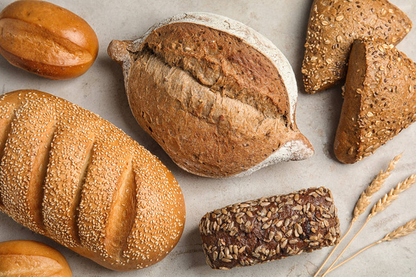 Different kinds of fresh bread on grey table, flat lay - Fotografie, Obrázek