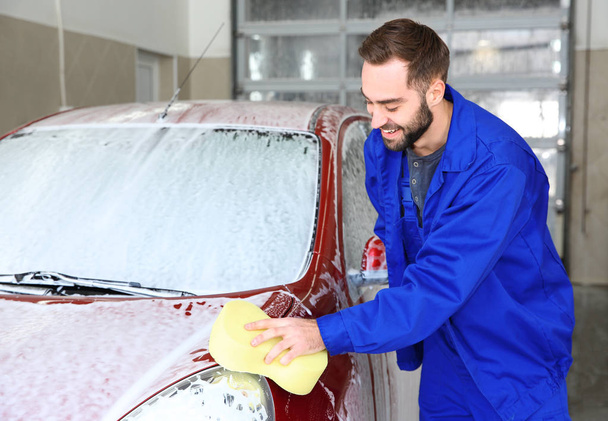 Worker cleaning automobile with sponge at professional car wash - Foto, Bild
