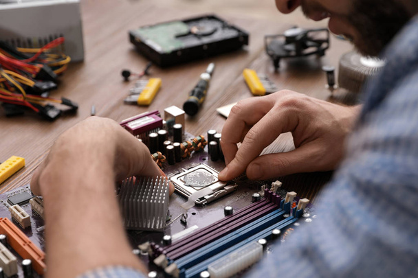 Male technician repairing motherboard at table, closeup - Photo, Image