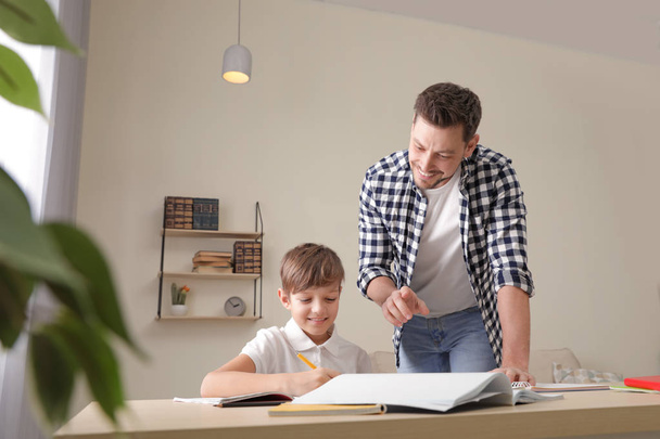 Dad helping his son with school assignment at home - Foto, immagini