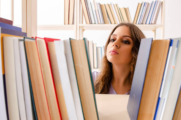 Jonge vrouwelijke student bereidt examens in de bibliotheek voor  - Foto, afbeelding