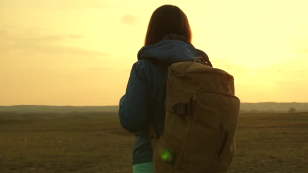 Vrijheid en onafhankelijkheid. Hiking. Mooi meisje reiziger met een rugzak gaat te voet bij zonsondergang. Toeristische meisje. Concept in de campagne. - Video