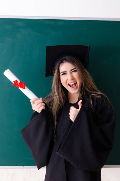 Estudiante graduada frente al tablero verde
  - Foto, imagen