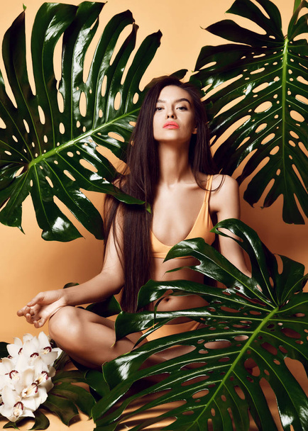 Young beautiful sexy woman with perfect smooth skin hold tropical leaves and orchid flowers - Foto, afbeelding