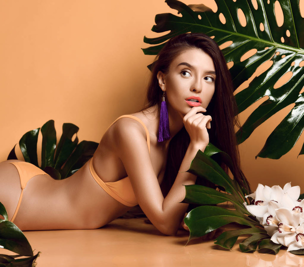 Joven hermosa mujer sexy con perfecta piel lisa sostienen hojas tropicales y flores de orquídea
 - Foto, imagen